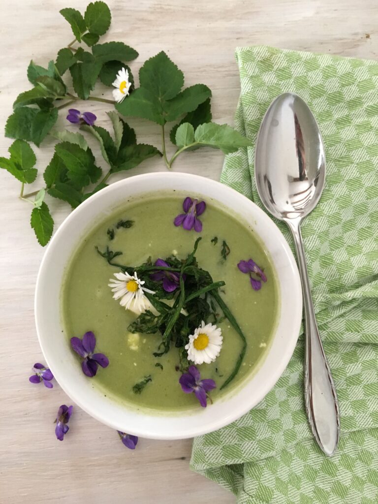 Gründonnerstagssuppe, grüne Suppe in Suppenschale mit Blüten Deko