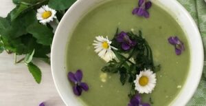 Gründonnerstagsuppe grüne Suppe mit Veilchen und Gänseblümchen als Dekoration